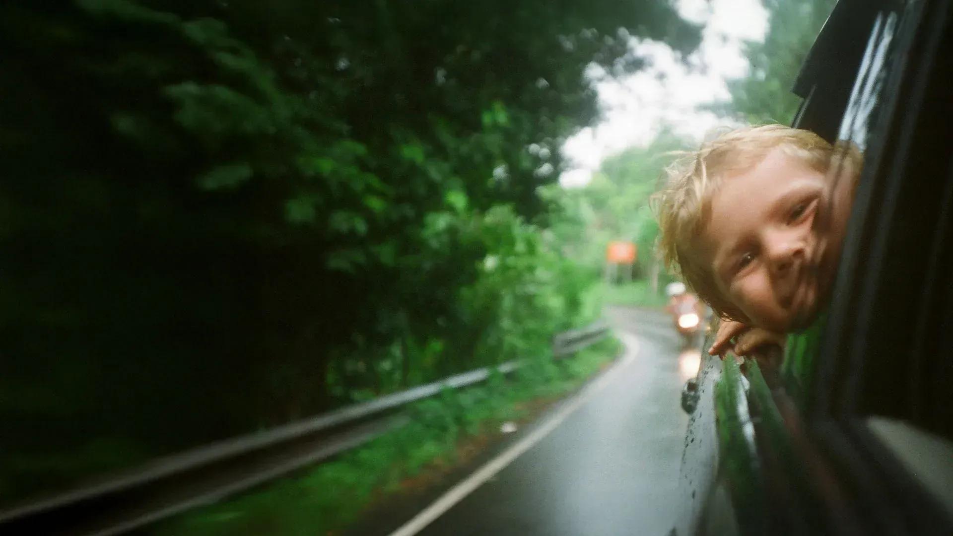 Niño en un auto, camino de ruta.