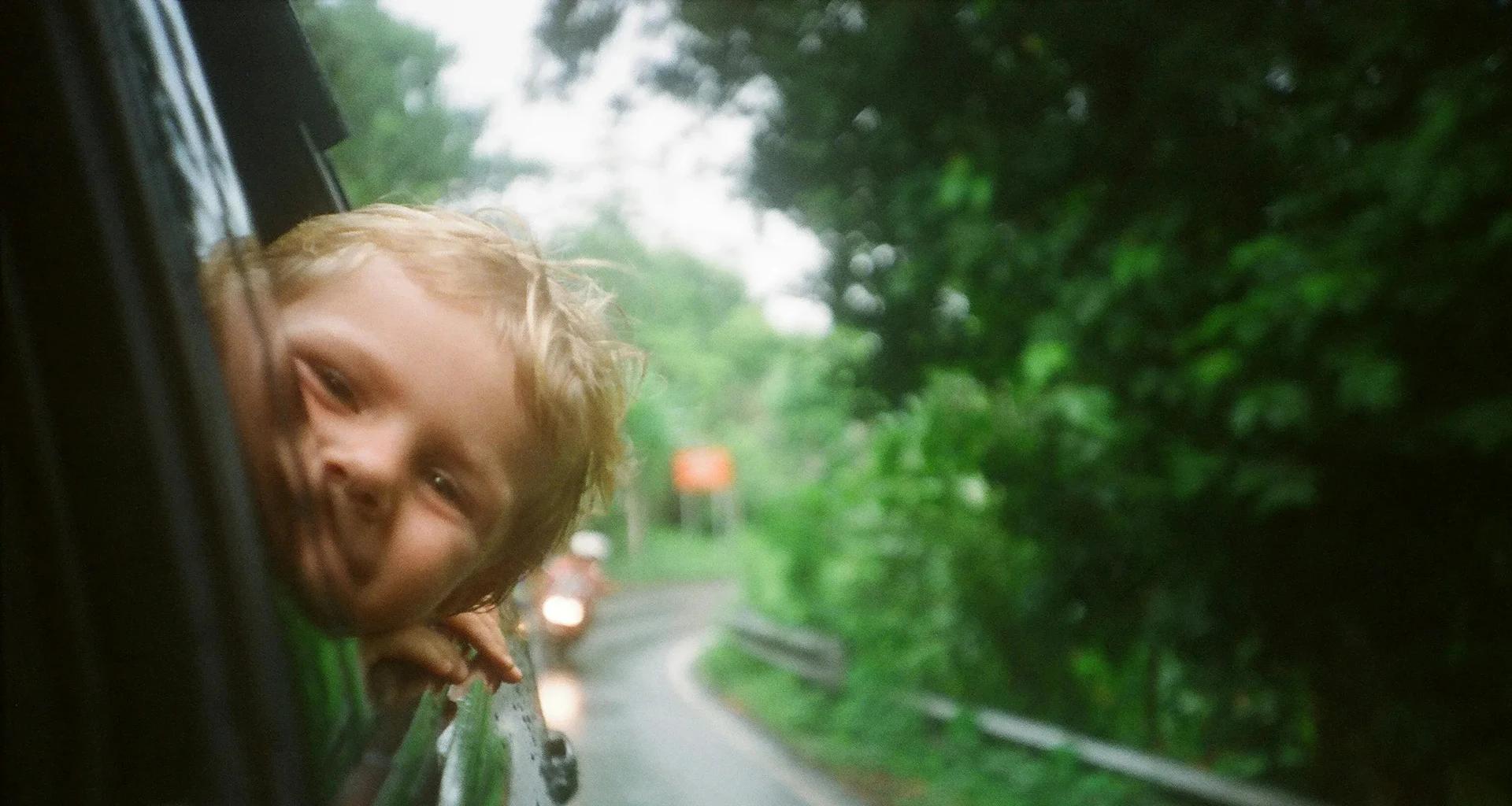 Niño en un auto, camino de ruta.